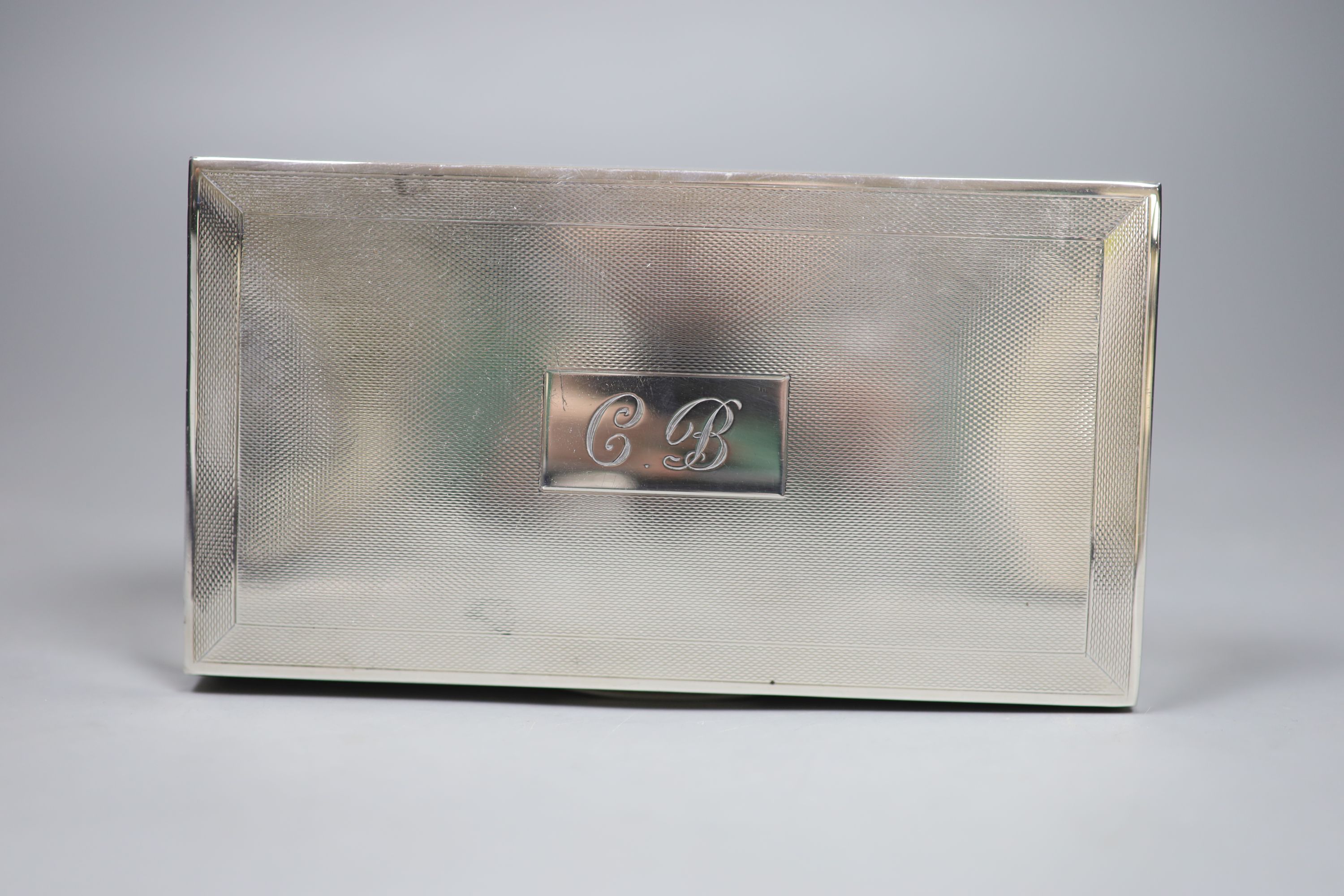 A 1960s engine turned silver mounted rectangular cigarette box, with engraved initials, 15.9cm, gross 14.5oz.